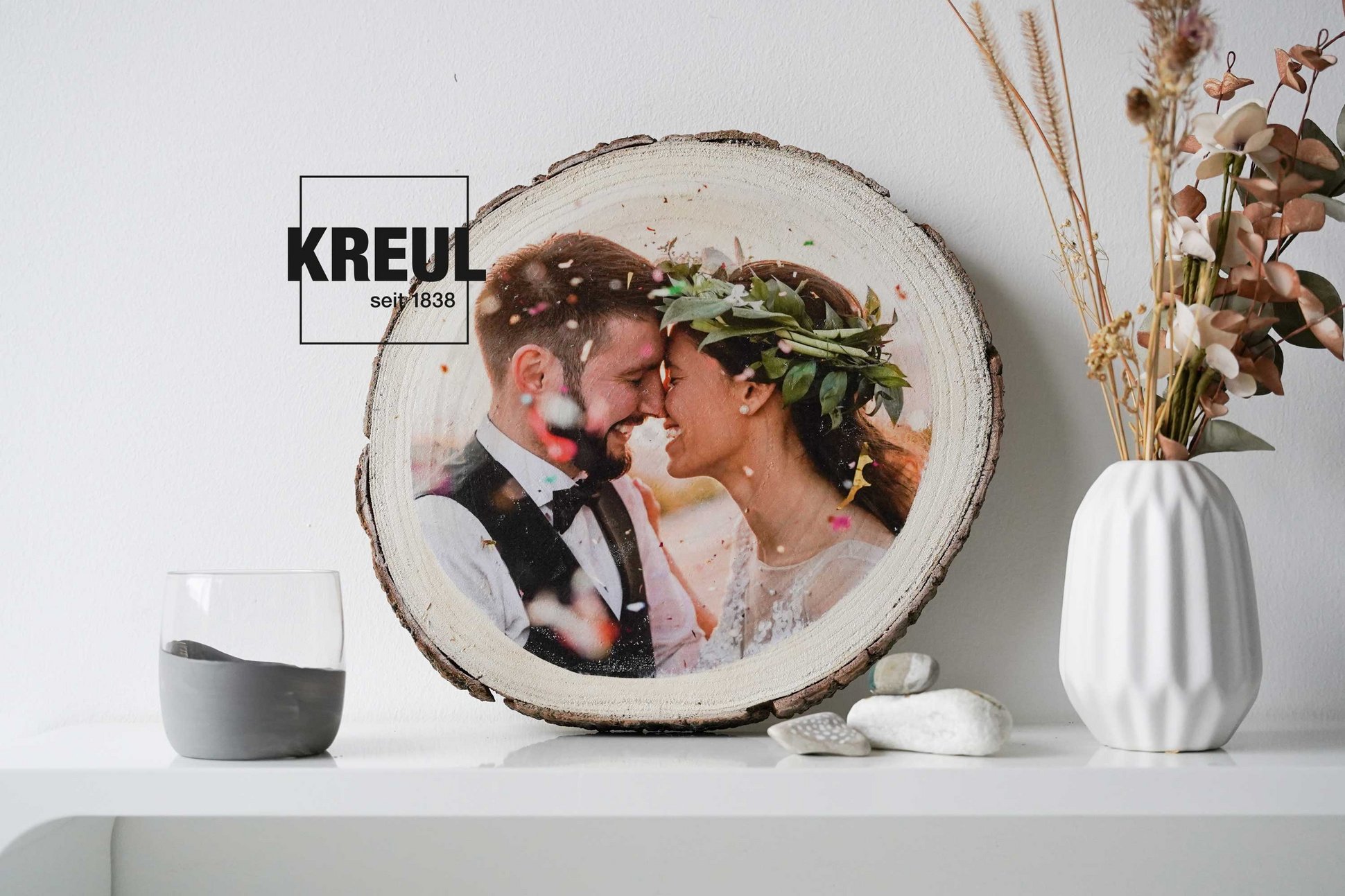Hochzeitsfoto Motiv auf Baumscheibe Holz übertragen KREUL Foto Transfer Potch Geschenk Idee Foto eines Hochzeitspaars auf einer Baumscheibe appliziert, daneben eine Vase und ein Windlicht