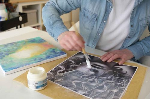 Frau streicht mit dem Pinsel und KREUL Foto Transfer Potch Kleber einen Druck ein