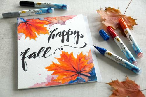 Handlettering Gemälde mit Herbstlaub neben Aquarell Markern