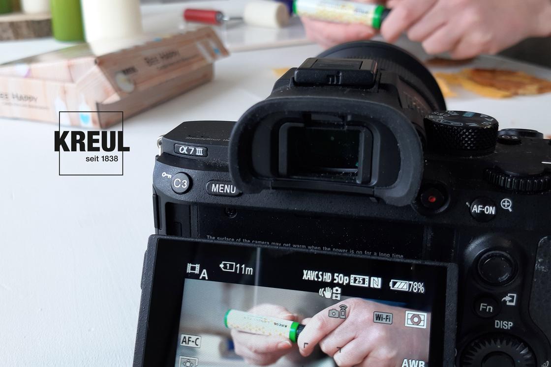 Kamera mit Händen, die Basteln im Hintergrund