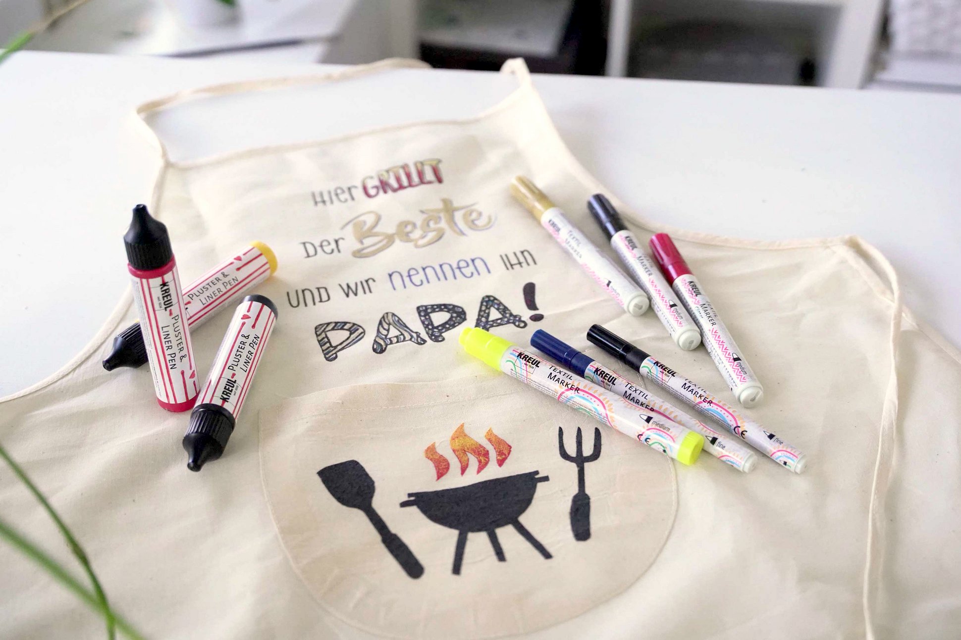 Step by Step Anleitung Lettering Grillschürze für Papa Vatertag Kinder Geschenkidee basteln malen Selbst bemalte Grillschürze mit KREUL Textil Markern und KREUL Pluster & Liner Pens
