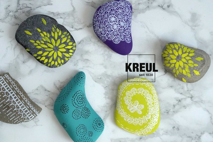 mit KREUL Acrylfarben verzierte, bunte Kieselsteine auf marmornem Untergrund 