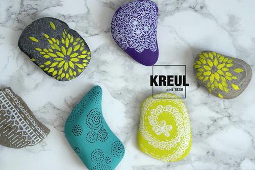 mit KREUL Acrylfarben verzierte, bunte Kieselsteine auf marmornem Untergrund 