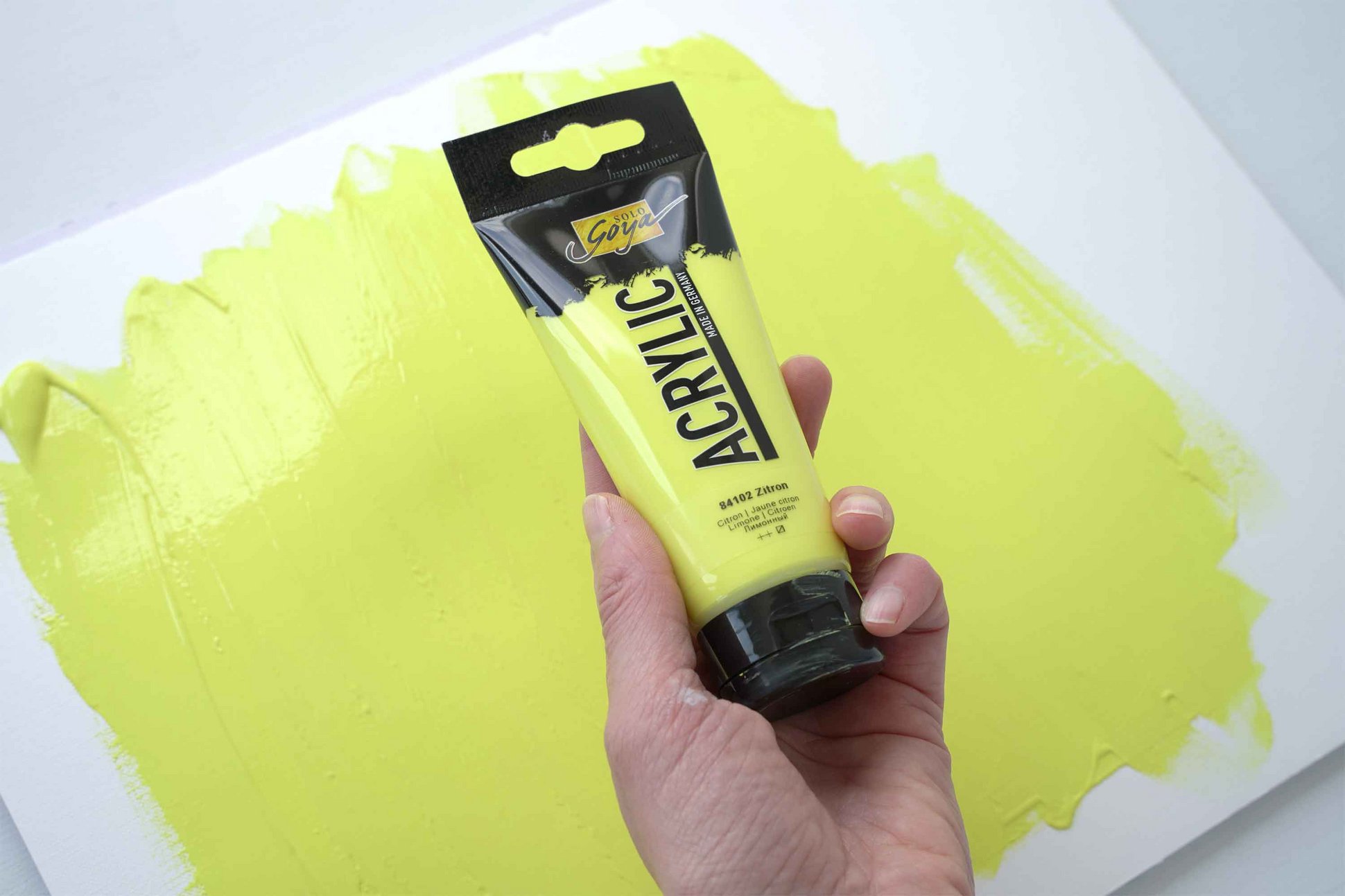 Farbtube SOLO GOYA Acrylic Zitron vor gelbem Hintergrund