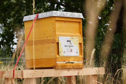 Bienenhaus aus Holz mit Schild Bee Happy und KREUL Logo