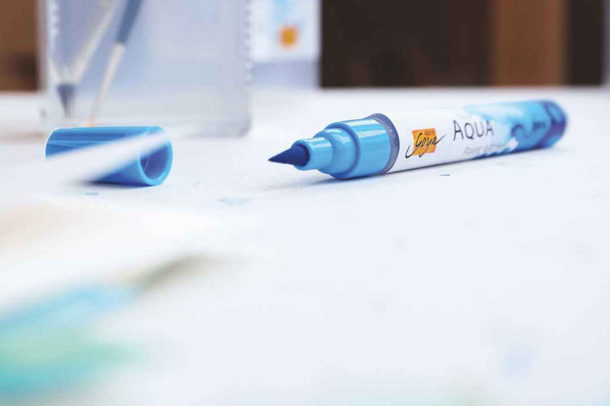 SOLO GOYA Aqua Paint Marker in Cyan neben Wasserglas und Pinsel