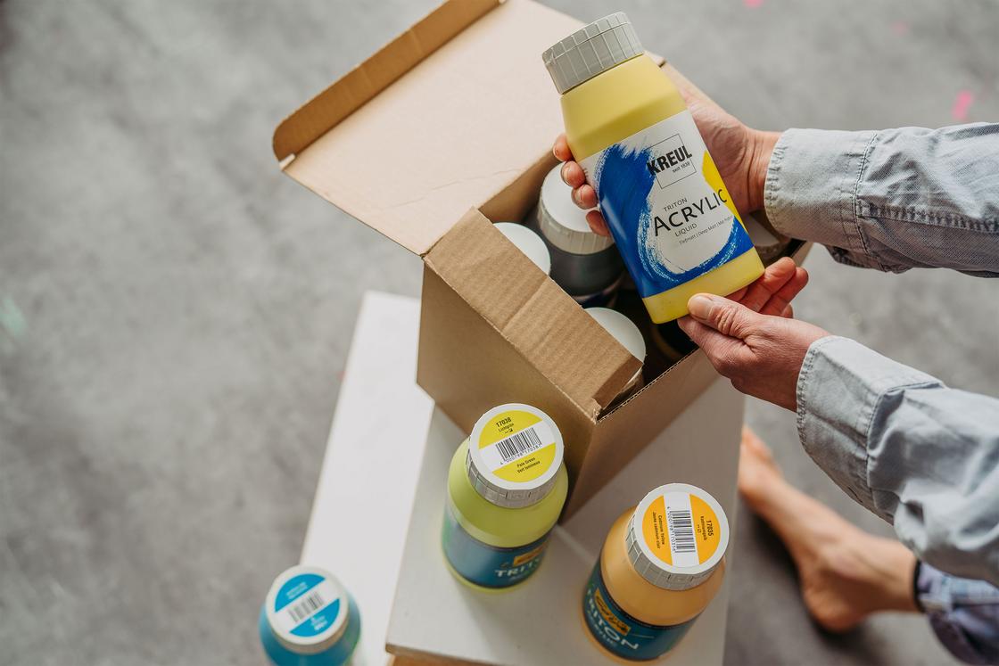 Geöffneter Karton mit KREUL Triton Acrylic Liquid Farbflaschen