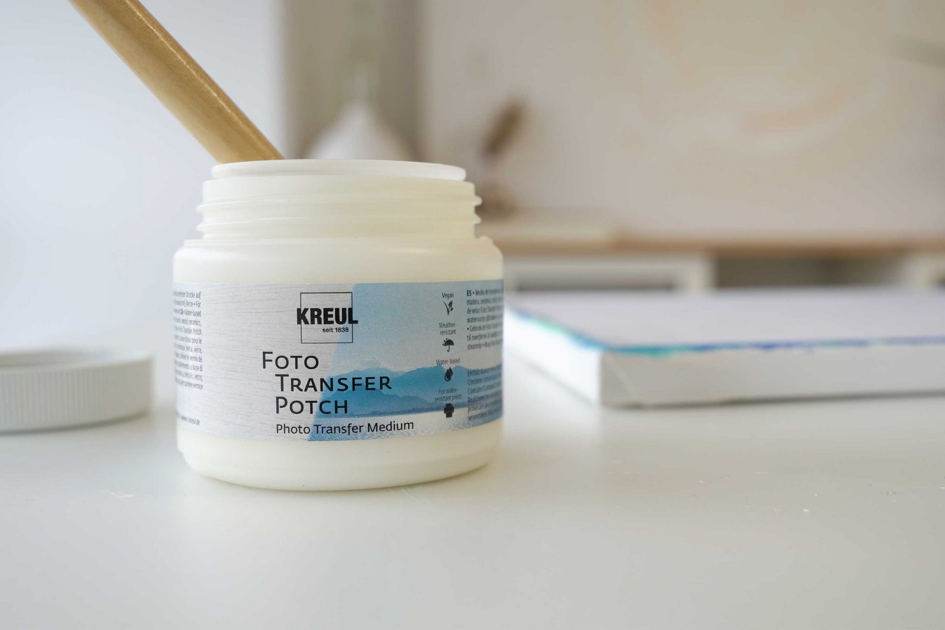 KREUL Foto Transfer Potch wasserfestes Übetragen von Fotomotiven und Zeitschriftenbildern auf Deko Gegenstände und Leinwand Dose mit KREUL Foto Transfer Potch und Leinwand im Hintergrund